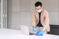 Businessman using microfiber cloth and alcohol sanitizer spray to clean laptop and table