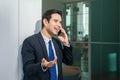 Businessman using mobile phone app texting outside of office in urban city with skyscrapers buildings in the background. Royalty Free Stock Photo