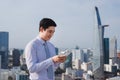 Businessman using mobile phone app texting outside of office in urban city with skyscrapers buildings in the background Royalty Free Stock Photo