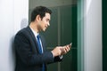 Businessman using mobile phone app texting outside of office in urban city with skyscrapers buildings in the background. Royalty Free Stock Photo