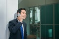 Businessman using mobile phone app texting outside of office in urban city with skyscrapers buildings in the background. Royalty Free Stock Photo