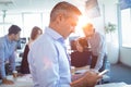 Businessman using mobile phone with team in background Royalty Free Stock Photo