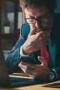 Businessman using mobile phone at work desk in office, checking electronic banking and finance app on smartphone Royalty Free Stock Photo