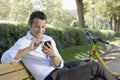 Businessman Using Palmtop Pilot On Park Bench