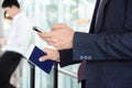 Businessman using smart phone while holding passport in another