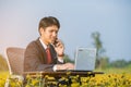 Businessman using smartphone and laptop in flower field Royalty Free Stock Photo