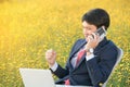 Businessman using smartphone and laptop in flower field Royalty Free Stock Photo