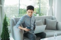 Businessman using smartphone and laptop writing on sofa in coffee shop Royalty Free Stock Photo