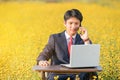 Businessman using smartphone and laptop in flower field Royalty Free Stock Photo