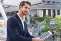 Businessman using tablet computer in his hands while standing on office building city. Executive handsome young man wear suit Royalty Free Stock Photo