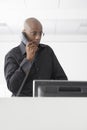 Businessman Using Telephone At Computer Desk Royalty Free Stock Photo