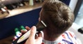 Hairstylist trimming man hair on occiput in barbershop
