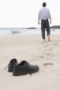 Businessman walking barefoot on beach