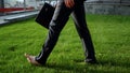 Businessman walking barefoot on green grass near office center, relaxation