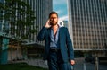 Businessman walking in city. Business man using mobile phone outside of office in urban city with skyscrapers buildings Royalty Free Stock Photo