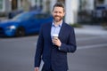 Businessman walking in city. Gray hair business man walk on city street. Business man walking outdoor, hold take away Royalty Free Stock Photo