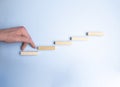 Businessman walking his fingers up a stairway made of wooden pegs in a conceptual image. Over navy blue background Royalty Free Stock Photo