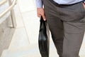 Businessman walking and holding a leather briefcase in his hand Royalty Free Stock Photo