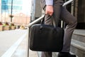 Businessman walking and holding a leather briefcase in his handss Modern city behind Royalty Free Stock Photo