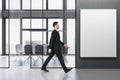 Businessman walking in modern concrete meeting room office interior with empty mock up banner, table, armchairs, window with city Royalty Free Stock Photo