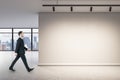 Businessman walking in  office interior with blank wall, mock up place and window with city view Royalty Free Stock Photo