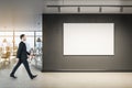 Businessman walking in  office interior with blank wall, mock up poster and window with city view Royalty Free Stock Photo