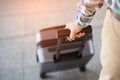 Businessman walking outside public transport building with luggage in rush hour. Business traveler pulling suitcase in modern airp Royalty Free Stock Photo