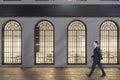 Businessman walking past business center exterior with windows and shadows at night