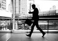 Businessman walking on the skywalk hastily. In his hand is a black leather briefcase. with flare light Royalty Free Stock Photo