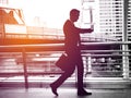 Businessman walking on the skywalk hastily. In his hand is a black leather briefcase. with flare light Royalty Free Stock Photo