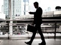 Businessman walking on the skywalk hastily. In his hand is a black leather briefcase. with flare light Royalty Free Stock Photo