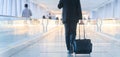 Businessman walking and wheeling a trolley suitcase at the lobby, talking on a mobile phone. Business travel concept. Royalty Free Stock Photo