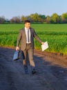 a businessman walks through a green grass field, the concept of business activity and freelancing