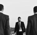 Businessman walks towards two men, defocused. Man with beard and serious face walks forward, close up.