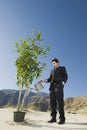 Businessman Watering Plant In Desert