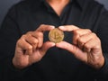 Businessman wearing a black shirt holding a bitcoin coin while standing with a gray background Royalty Free Stock Photo