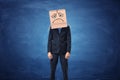 Businessman wearing cardboard box with drawn sad face on his head Royalty Free Stock Photo