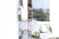 Businessman wearing glasses sitting down drinking an expresso coffee