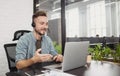 Businessman wearing headphones having meeting online. Young man using laptop computer in office