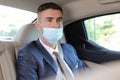 Businessman wearing protective mask incorrectly in backseat