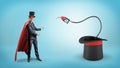 A businessman wearing a red cape and a big illusionist`s hat shows a fuel nozzle inside a large magician`s hat.