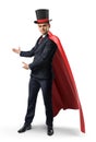 A businessman wearing a red cape and a big illusionist`s hat shows something on a white background.