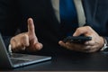 Businessman wearing suit thumbs up to touch and using smartphone working laptop, businessman using mobile phone search or social