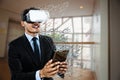 Composite image of businessman wearing vr glasses while using tablet Royalty Free Stock Photo