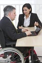 Businessman in wheelchair with assistant