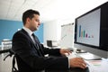 Businessman in wheelchair working with computer in office