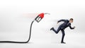 A businessman on white background running away from a red gas nozzle attached to a black hose.