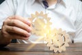 Businessman in white shirt connects two wooden gears. Symbolism of establishing business processes and communication. Increase