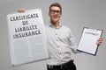 Man holds a poster with inscription certificate of liability insurance and an empty certificate isolated Royalty Free Stock Photo