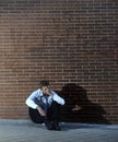 Businessman who lost job lost in depression sitting on city street corner Royalty Free Stock Photo